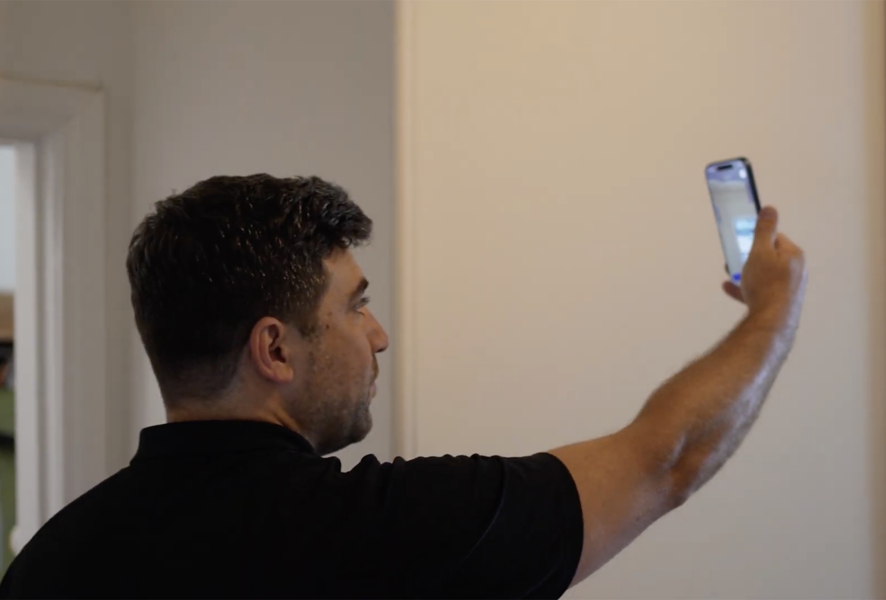 An agent holding his phone up to scan the corner of a room